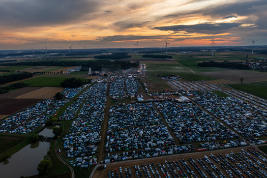 Herzogenaurach Germany 24 July 2025 Aerial view of the Open Beatz Festival campsite with thousands of tents and cars under a sunset sky with wind turbines in the distance.