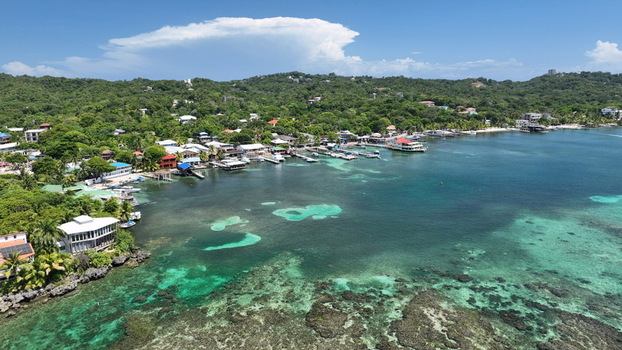 Aerial view of West End with its turquoise waters coral reefs boats moored along the coast and lush green hills in the background in West End Bay Islands Department Honduras. Aerial view of West End with its turquoise waters coral reefs boats moored along the coast and lush green hills in the background in West End Bay Islands Department Honduras.