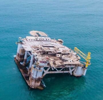 Aerial view of an offshore oil platform surrounded by deep blue ocean waters featuring a helipad and industrial crane structures in Ghana. Aerial view of an offshore oil platform surrounded by deep blue ocean waters featuring a helipad and industrial crane structures in Ghana.