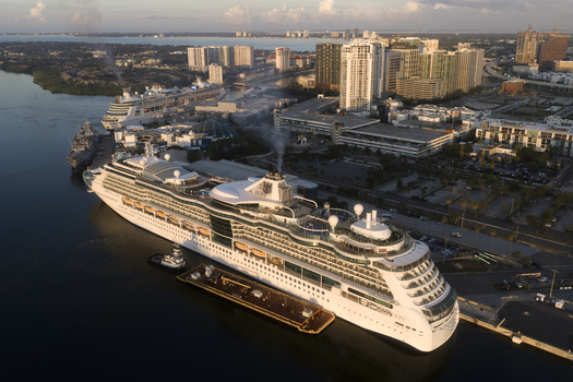 Tampa United States 04 July 2026 Aerial view of Tampa Cruise Terminal 6 with a large cruise ship docked at the pier surrounded by urban buildings and the waterfront under soft evening light.