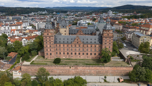 Aerial view of Schloss Johannisburg a historic red sandstone palace with four towers surrounded by urban architecture and green spaces in Aschaffenburg Bayern Germany.