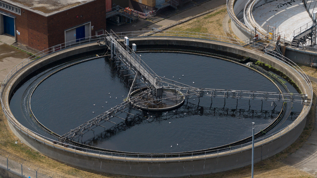 Aerial view of the M Group Water treatment facility featuring a large circular sedimentation tank with a rotating bridge mechanism in Dartford England United Kingdom.