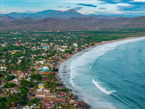 Aerial view of the coastal town of Punta Perula with its sandy beach turquoise ocean waves palm trees and colorful buildings in Punta Perula Jalisco Mexico. Aerial view of the coastal town of Punta Perula with its sandy beach turquoise ocean waves palm trees and colorful buildings in Punta Perula Jalisco Mexico.