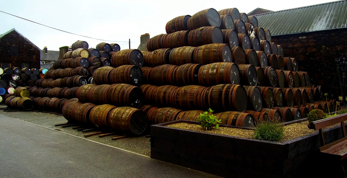 Aerial view of Bruichladdich Distillery with stacks of wooden whisky barrels stored outdoors in Bruichladdich Scotland United Kingdom.