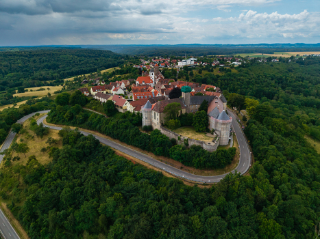 Aerial view of Schloss Waldenburg a historic castle complex on a hill surrounded by forests winding roads and traditional rooftops under a cloudy sky in Waldenburg Sachsen Germany. Aerial view of Schloss Waldenburg a historic castle complex on a hill surrounded by forests winding roads and traditional rooftops under a cloudy sky in Waldenburg Sachsen Germany.