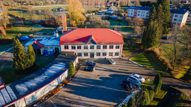 Burtnieki Valmiera Municipality Latvia 22 November 2025 Aerial view of a rural school with a red roof surrounded by a parking lot green lawns and trees on a sunny autumn day.