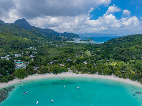 Aerial view of turquoise waters meeting pristine white sands beneath lush green hillsides revealing the tranquil beauty of the coast Victoria Mahe Island Seychelles. Aerial view of turquoise waters meeting pristine white sands beneath lush green hillsides revealing the tranquil beauty of the coast Victoria Mahe Island Seychelles.