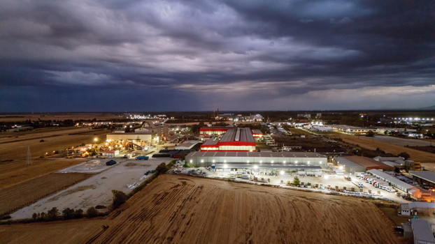 Aerial view of an industrial facility at night with illuminated warehouses storage yards and surrounding fields under a dramatic stormy sky in Sremska Mitrovica Vojvodina Serbia. Aerial view of an industrial facility at night with illuminated warehouses storage yards and surrounding fields under a dramatic stormy sky in Sremska Mitrovica Vojvodina Serbia.