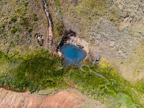 Aerial view of the geothermal pool in Grensdalur surrounded by volcanic hills and green vegetation in Sveitarfelagid Olfus Iceland. Aerial view of the geothermal pool in Grensdalur surrounded by volcanic hills and green vegetation in Sveitarfelagid Olfus Iceland.