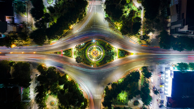 Aerial view of Monumen Bambu Runcing roundabout at night with vibrant light trails from traffic and illuminated greenery in Kecamatan Genteng Jawa Timur Indonesia. Aerial view of Monumen Bambu Runcing roundabout at night with vibrant light trails from traffic and illuminated greenery in Kecamatan Genteng Jawa Timur Indonesia.