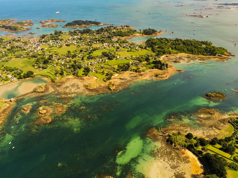 Aerial view of the island of Brehat featuring lush green fields stone houses rocky coastlines and turquoise waters Ile de Brehat Brittany France.