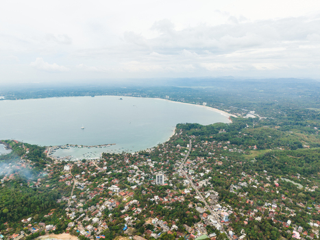 Aerial view of the coastal town featuring a large bay with boats sandy beaches and dense tropical vegetation under a cloudy sky Mirissa Southern Province Sri Lanka. Aerial view of the coastal town featuring a large bay with boats sandy beaches and dense tropical vegetation under a cloudy sky Mirissa Southern Province Sri Lanka.