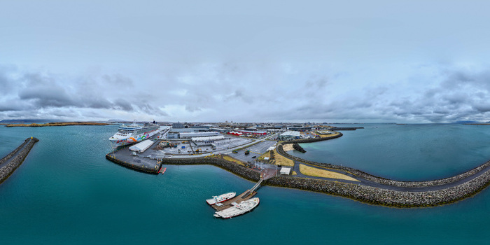 Aerial view of the Laugarnes peninsula with a cruise ship at the harbor industrial buildings and a breakwater under an overcast sky in Reykjavik Reykjavikurborg Iceland.