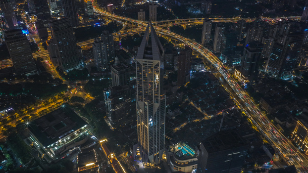 Aerial view of the illuminated Tomorrow Square skyscraper and busy highway interchanges at night in Shanghai Shanghai China.