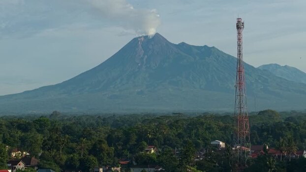 Aerial view of Mount Merapi volcano with smoke and a tower Indonesia.