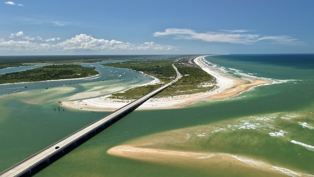 Aerial view of Matanzas Inlet showing the bridge crossing the water sandy beaches lush vegetation and the Atlantic Ocean under a clear blue sky in St. Johns County Florida United States. Aerial view of Matanzas Inlet showing the bridge crossing the water sandy beaches lush vegetation and the Atlantic Ocean under a clear blue sky in St. Johns County Florida United States.