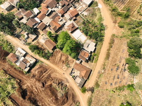Aerial view of residential houses with terracotta roofs dirt roads and agricultural fields in the rural landscape of Garut West Java Indonesia. Aerial view of residential houses with terracotta roofs dirt roads and agricultural fields in the rural landscape of Garut West Java Indonesia.