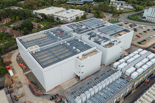 Aerial view of a large data center complex with rooftop HVAC units and surrounding infrastructure in the United Kingdom.