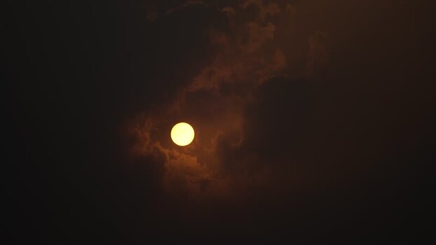 View of the sun shining through dark clouds in Bangladesh.
