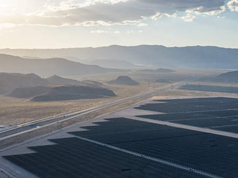 Aerial view of a vast solar farm with rows of photovoltaic panels next to a highway in the desert landscape under a hazy sunset in Enterprise Nevada United States. Aerial view of a vast solar farm with rows of photovoltaic panels next to a highway in the desert landscape under a hazy sunset in Enterprise Nevada United States.