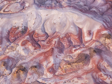 Aerial view of the colorful Bentonite Hills with striped red and grey clay formations rolling desert terrain and natural geological patterns in Hanksville Utah United States.