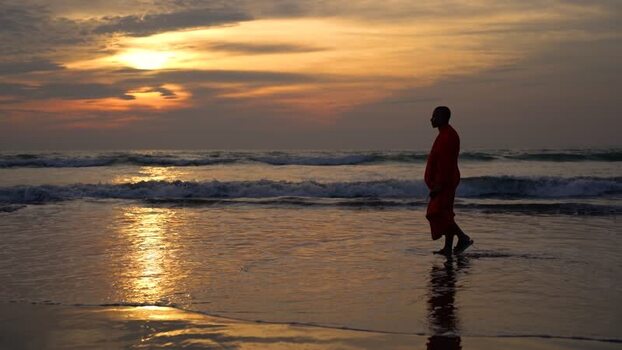 View of a monk walking on the beach at sunset in Bangladesh. View of a monk walking on the beach at sunset in Bangladesh.