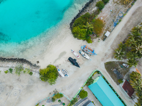 Aerial view of boats resting on the sandy shore where turquoise waters meet the land Vashafaru Island Thiladhummathi Atoll Maldives. Aerial view of boats resting on the sandy shore where turquoise waters meet the land Vashafaru Island Thiladhummathi Atoll Maldives.