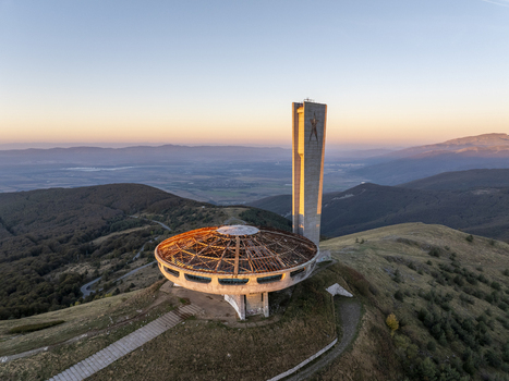 Aerial view of the iconic Buzludzha Monument a brutalist structure perched on a mountain peak at sunset surrounded by rolling hills and autumn forests in Stara Zagora Bulgaria. Aerial view of the iconic Buzludzha Monument a brutalist structure perched on a mountain peak at sunset surrounded by rolling hills and autumn forests in Stara Zagora Bulgaria.