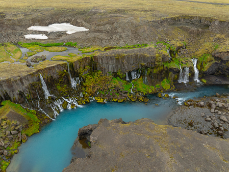 Aerial view of Sigoldugljufur canyon featuring turquoise river waters cascading down moss covered basalt cliffs with patches of snow in the highlands of Rangarthing ytra Iceland. Aerial view of Sigoldugljufur canyon featuring turquoise river waters cascading down moss covered basalt cliffs with patches of snow in the highlands of Rangarthing ytra Iceland.