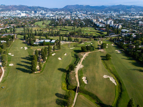 Aerial view of Wilshire Country Club featuring lush green fairways sand bunkers and mature trees with the Los Angeles skyline in the background Los Angeles California United States. Aerial view of Wilshire Country Club featuring lush green fairways sand bunkers and mature trees with the Los Angeles skyline in the background Los Angeles California United States.