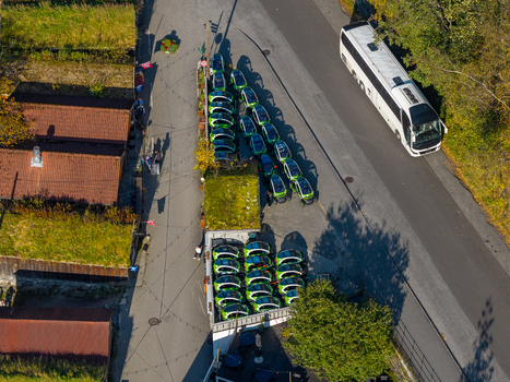 Aerial view of small electric rental cars parked in a lot next to a road and a bus in Geiranger More og Romsdal Norway. Aerial view of small electric rental cars parked in a lot next to a road and a bus in Geiranger More og Romsdal Norway.