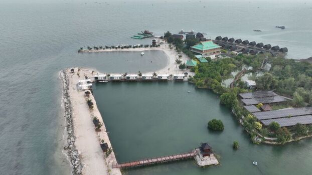 Aerial view of Pulau Lima Resort featuring overwater bungalows a sandy beach and a wooden pier extending into the calm sea in Kasemen Banten Indonesia. Aerial view of Pulau Lima Resort featuring overwater bungalows a sandy beach and a wooden pier extending into the calm sea in Kasemen Banten Indonesia.