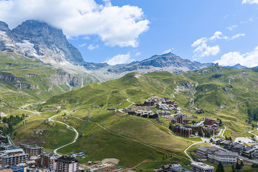 Aerial view of the mountain resort of Breuil Cervinia nestled in the Alps with green slopes ski lifts and the Matterhorn in the background Breuil Cervinia Aosta Valley Italy. Aerial view of the mountain resort of Breuil Cervinia nestled in the Alps with green slopes ski lifts and the Matterhorn in the background Breuil Cervinia Aosta Valley Italy.