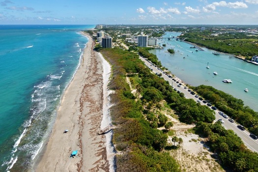 Aerial view of the sandy coastline turquoise ocean water and lush green vegetation along the shoreline Jupiter Florida United States. Aerial view of the sandy coastline turquoise ocean water and lush green vegetation along the shoreline Jupiter Florida United States.