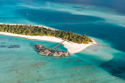 Aerial view of overwater bungalows on wooden walkways leading to a tropical island with white sand beaches and turquoise waters near Kudahuvadhoo Dhaalu Atoll Maldives. Aerial view of overwater bungalows on wooden walkways leading to a tropical island with white sand beaches and turquoise waters near Kudahuvadhoo Dhaalu Atoll Maldives.