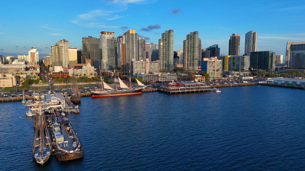 Aerial view of the San Diego skyline and waterfront featuring historic sailing ships docked at the North Embarcadero and modern skyscrapers in San Diego California United States.