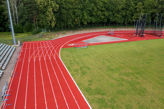 Aerial view of red running track and green athletic field surrounded by lush trees and stadium seating Vilnius County Lithuania. Aerial view of red running track and green athletic field surrounded by lush trees and stadium seating Vilnius County Lithuania.