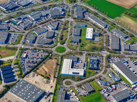 Aerial view of the business district with its roundabouts and building complexes nestled between green fields and industrial architecture Sausheim Grand Est France.
