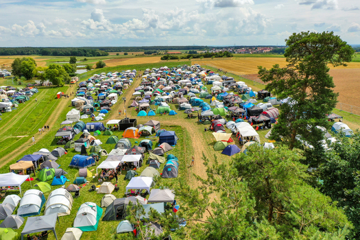 Herzogenaurach Germany 24 July 2025 Aerial view of Open Beatz Festival campsite with numerous colorful tents spread across green fields under a cloudy sky.