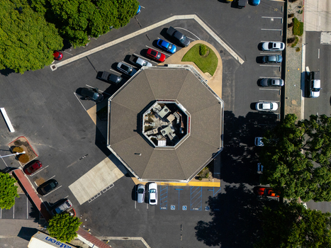 Aerial view of an octagonal building surrounded by a parking lot with parked cars and green trees in Carson California United States.