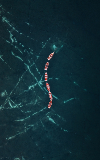 Aerial view of Lake Braies with a line of wooden rowing boats floating on the dark turquoise water surface in Braies Trentino Alto Adige Italy. Aerial view of Lake Braies with a line of wooden rowing boats floating on the dark turquoise water surface in Braies Trentino Alto Adige Italy.