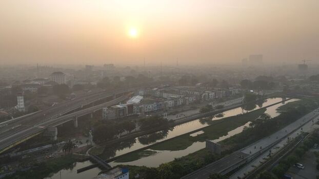 Aerial view of the urban landscape featuring a river elevated highway and buildings under a hazy sunset sky in Bekasi Barat West Java Indonesia. Aerial view of the urban landscape featuring a river elevated highway and buildings under a hazy sunset sky in Bekasi Barat West Java Indonesia.