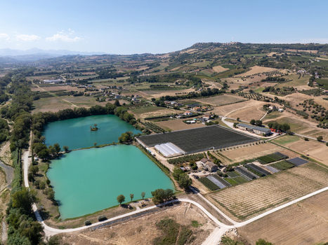 Aerial view of Laghi Santarelli with turquoise lakes agricultural fields and greenhouses set in the rolling hills of Moresco Marche Italy.