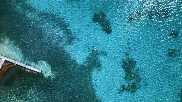 Aerial view of a person swimming in turquoise water Honduras.