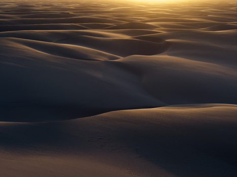 Aerial view of the vast sand dunes of Parque Nacional dos Lencois Maranhenses with golden sunset light hitting the crests and deep shadows Lencois Maranhenses MA Brazil. Aerial view of the vast sand dunes of Parque Nacional dos Lencois Maranhenses with golden sunset light hitting the crests and deep shadows Lencois Maranhenses MA Brazil.