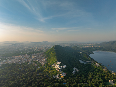 Aerial view of the Monsoon Palace perched on a lush green hill overlooking Fateh Sagar Lake and the city of Udaipur Rajasthan India.