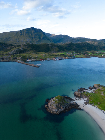 Aerial view of the coastal village of Tangstad featuring a small harbor sandy beaches and turquoise waters against a backdrop of rugged mountains in Leknes Nordland Norway. Aerial view of the coastal village of Tangstad featuring a small harbor sandy beaches and turquoise waters against a backdrop of rugged mountains in Leknes Nordland Norway.