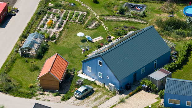 Aerial view of Ecodorp Bolderburen featuring a blue house with solar panels a greenhouse a vegetable garden and a small wooden shed in Almere Flevoland Netherlands. Aerial view of Ecodorp Bolderburen featuring a blue house with solar panels a greenhouse a vegetable garden and a small wooden shed in Almere Flevoland Netherlands.