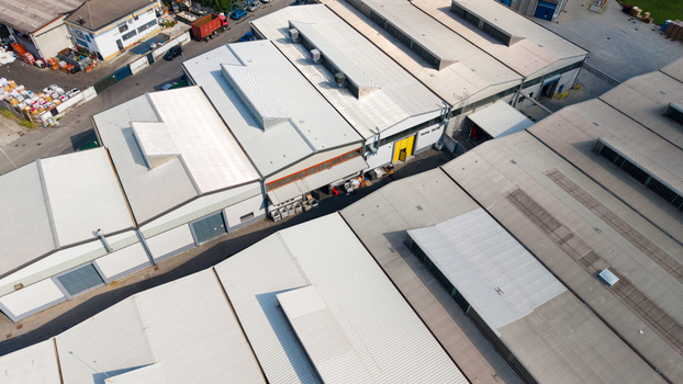 Aerial view of warehouse roofs in an industrial zone with metal structures and skylights in Milan Lombardy Italy.