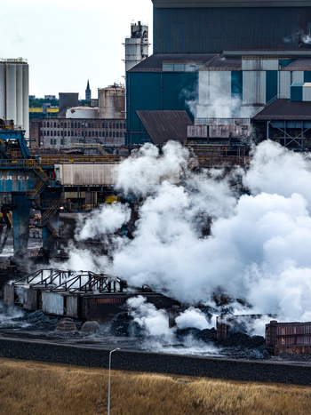 Aerial view of Tata Steel industrial complex with heavy smoke emissions large metal structures and industrial machinery in Velsen Noord Noord Holland Netherlands. Aerial view of Tata Steel industrial complex with heavy smoke emissions large metal structures and industrial machinery in Velsen Noord Noord Holland Netherlands.